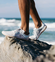 Vivo Barefoot Primus Lite III being worn standing on a rock in front of the sea