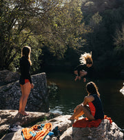 Three women jumping into a natural pool