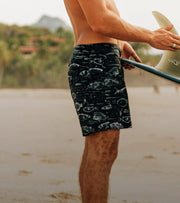 Man on beach wearing NHM print board shorts