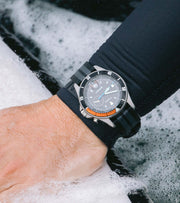 Man wearing Finisterre + Timex watch whilst putting on a wetsuit